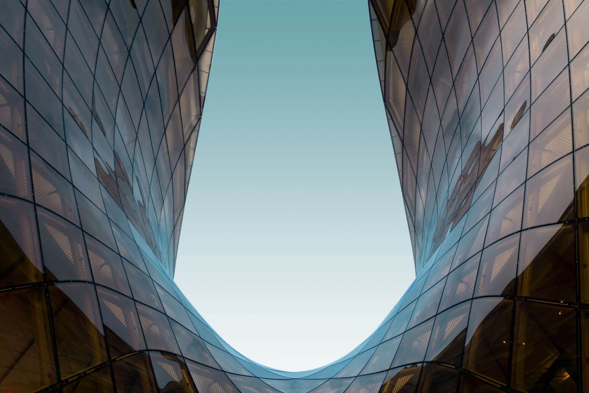 Modern glass buildings with a curved design against a clear sky.