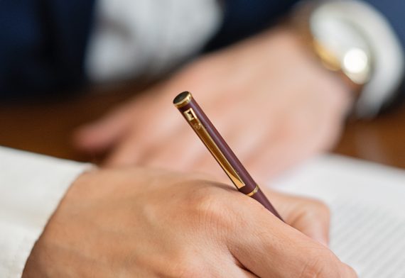 Person signing a document with pen.