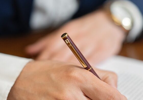 Person signing a document with pen.